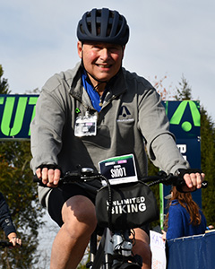 Dr. Weiner wears a helmet and rides a bike across the finish line at this year's BellRinger